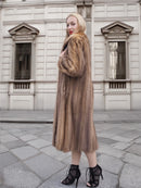 a woman in a fur coat standing on a sidewalk