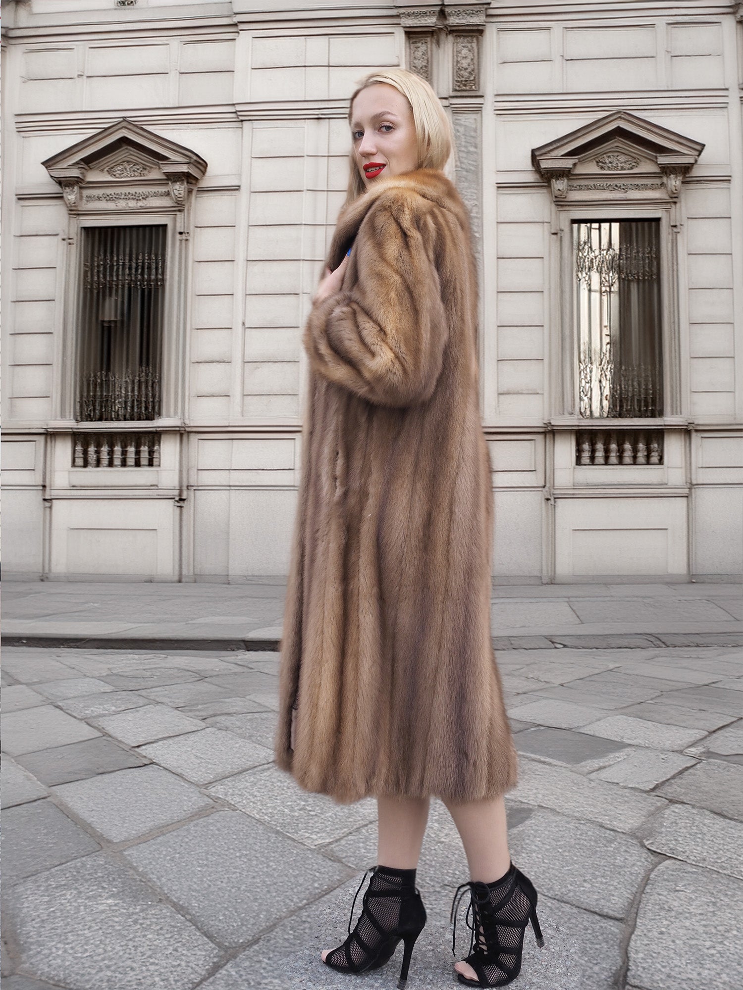 a woman in a fur coat standing on a sidewalk