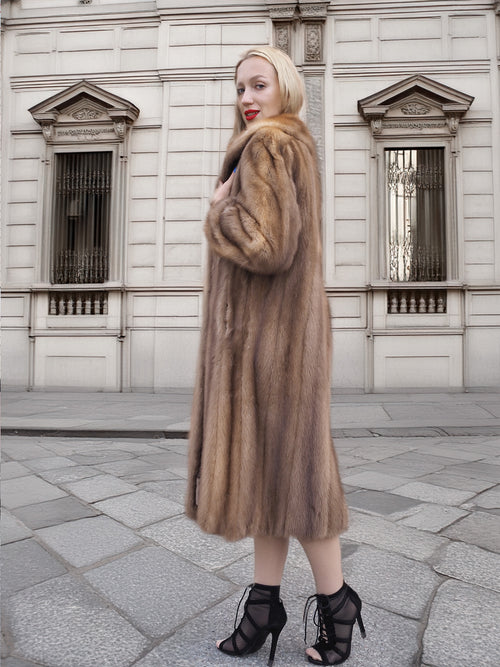 a woman in a fur coat standing on a sidewalk