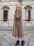 a woman in a fur coat standing on a sidewalk