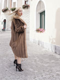 a woman in a fur coat standing on a cobblestone street