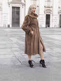 a woman in a fur coat standing on a sidewalk