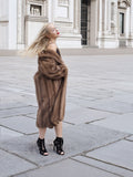 a woman in a fur coat standing on a sidewalk