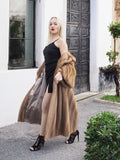 Elegant woman in vintage pastel Canadian brown mink fur coat and long tulle skirt, posing in front of ornate building entrance.