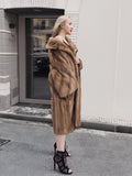 Elegant pastel Canadian brown mink fur coat with fur collar, full-length silhouette, and high-heeled boots, displayed in an urban setting.