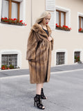 Elegant woman wearing a vintage pastel Canadian brown mink fur coat in front of a building with flower planters.