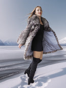 Woman in a fur coat standing on a snowy landscape with mountains in the background