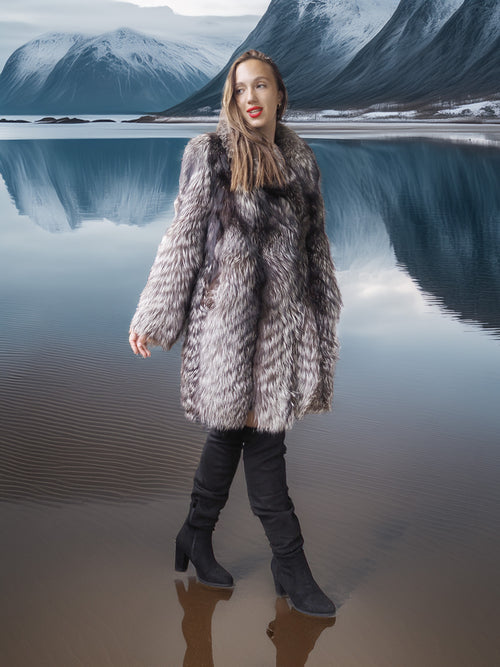 Woman in a fur coat standing in front of a mountainous landscape with a lake.
