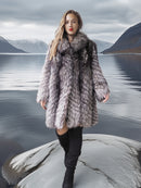 Woman in a fur coat standing on a rock with a scenic mountain and lake background