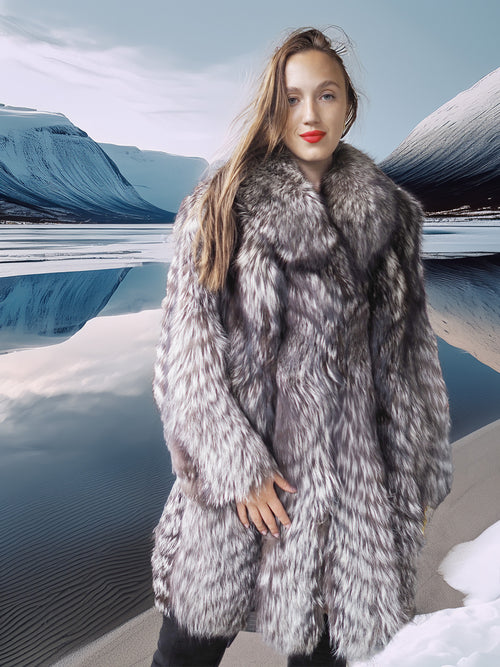 Woman wearing a fur coat standing in a snowy landscape with mountains in the background