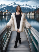 Woman in a fur coat standing on a wooden bridge with mountains and lake in the background
