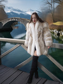 Woman in a fur coat standing on a wooden bridge with mountains in the background