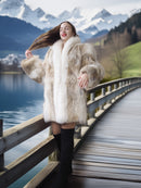 Woman in a fur coat standing on a wooden bridge with mountains and lake in the background