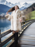 Woman in a fur coat standing on a wooden bridge with mountains and lake in the background