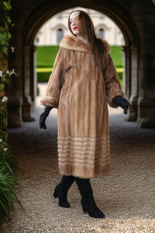 Tan mink fur long coat with hood and ribbed hem, seen full length with black boots