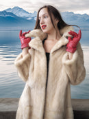 Woman wearing a fur coat and red gloves with a mountainous landscape in the background
