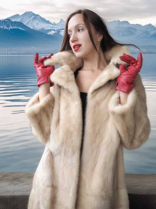 Woman wearing a fur coat and red gloves with a mountainous landscape in the background