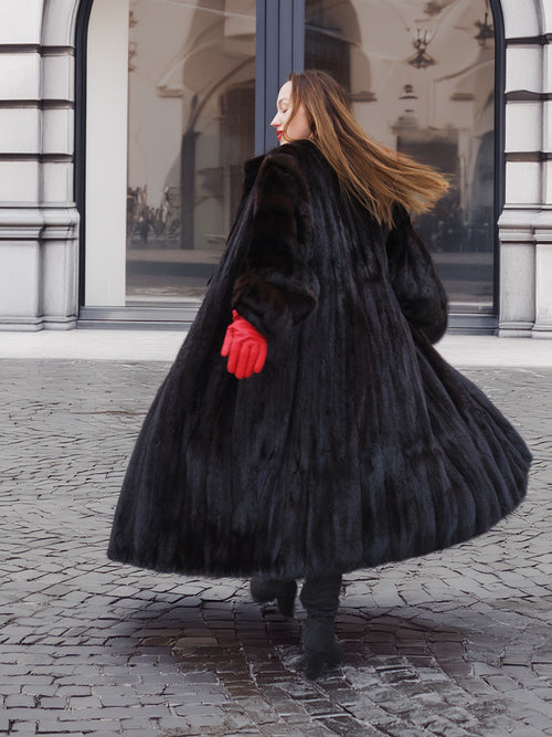 Classic black mink fur coat in motion, flaring out to show full volume and texture. Luxurious cold-weather fashion in dark ranch mink.