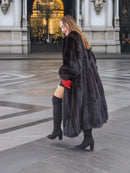 Woman walking in black mink fur coat, showing coat’s movement and volume. Premium fur fashion for winter elegance.
