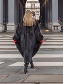 Back view of long black mink fur coat with natural sheen, worn with red gloves and boots. Sophisticated winter outerwear.