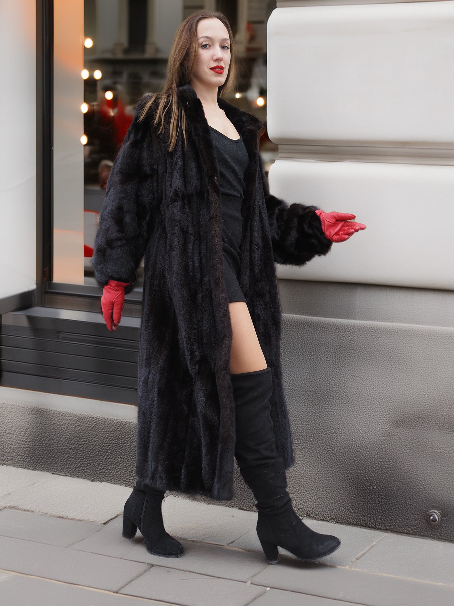 Model walking in black mink fur coat with red gloves and boots. Classic fur coat design with luxurious texture and warmth.
