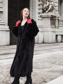 Classic black mink fur coat worn with red gloves, showcasing soft texture and elegant silhouette. Luxury outerwear for cold climates.