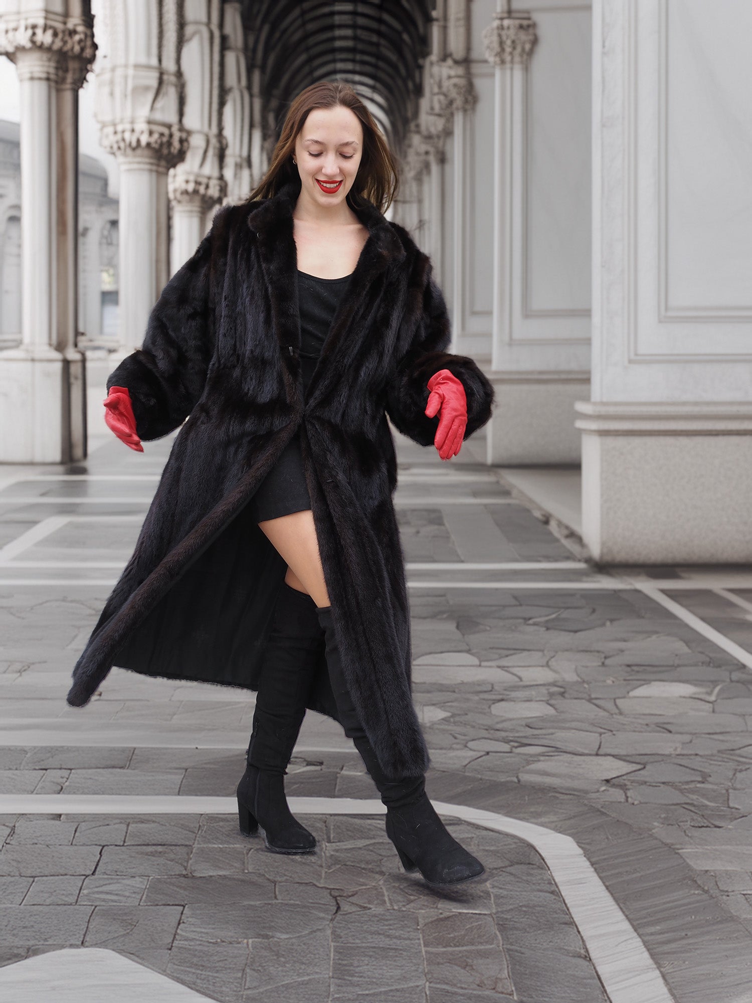 Model twirling in black mink fur coat with red gloves, showing coat’s volume and flow. Premium winter fashion outerwear.