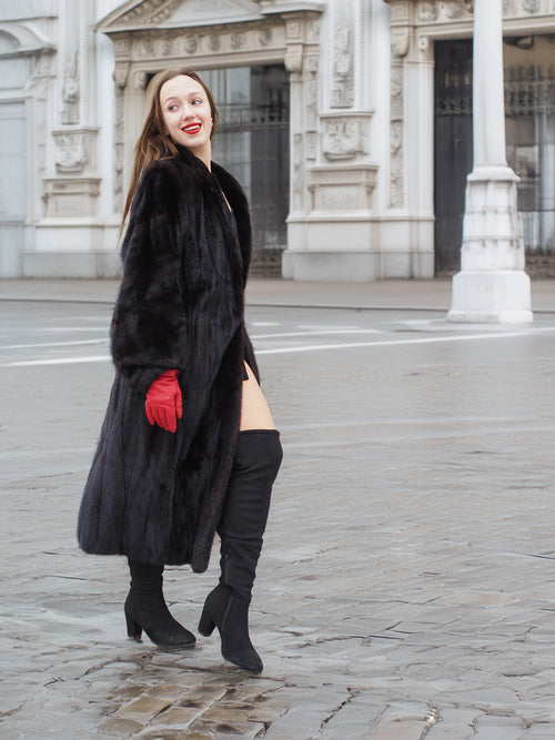 Elegant black mink fur coat styled with red gloves and boots. Full-length design perfect for luxury winter wardrobes.