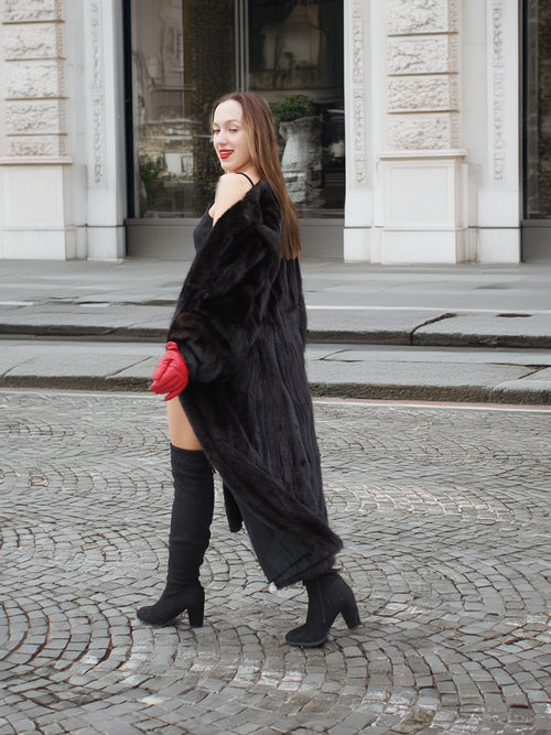 Side view of woman in dark ranch black mink fur coat, walking confidently. Warm and stylish fur outerwear for winter.
