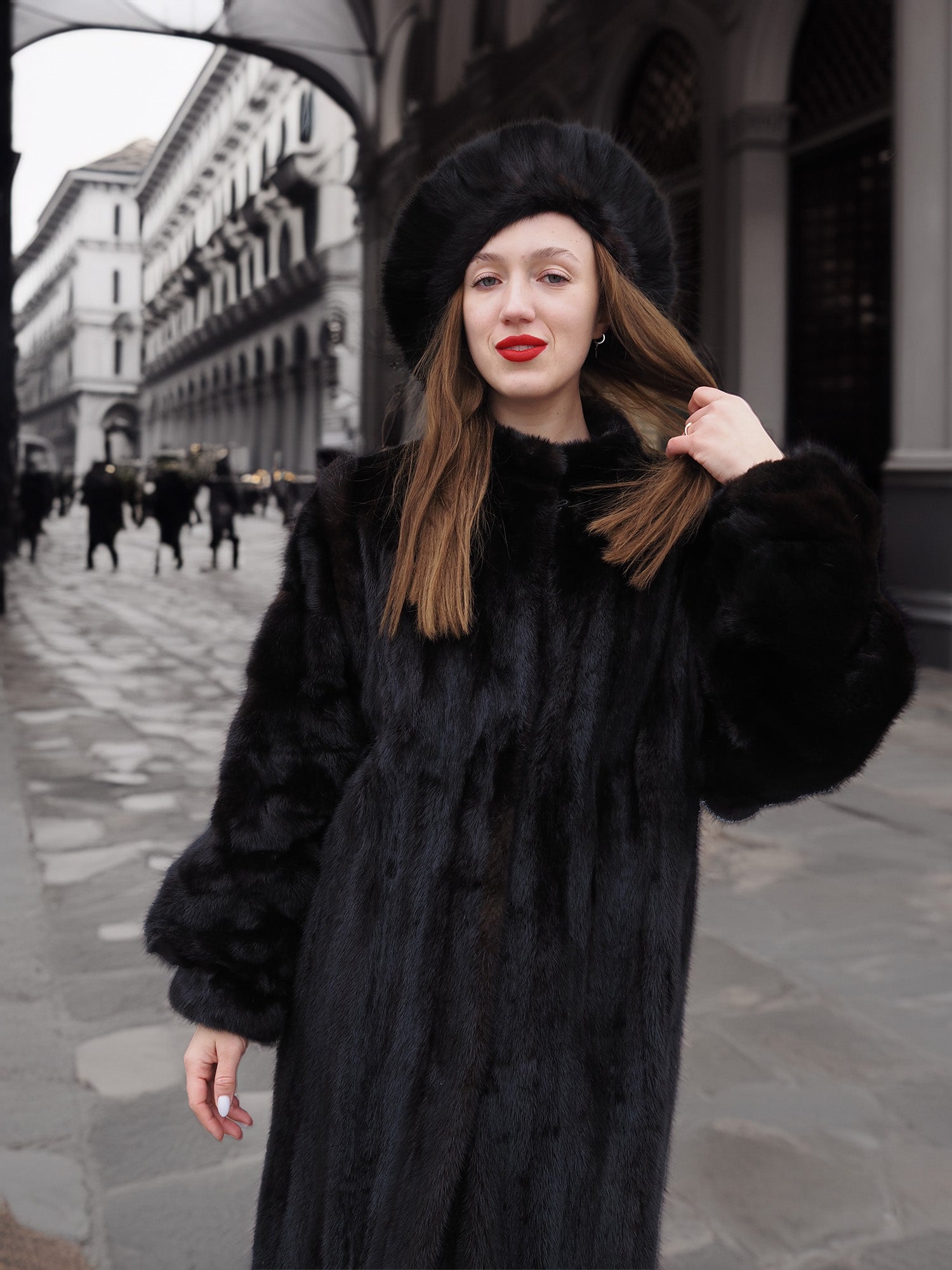 Woman wearing a dark ranch black mink fur coat with small round collar and matching hat. Stylish and warm outerwear for winter fashion.
