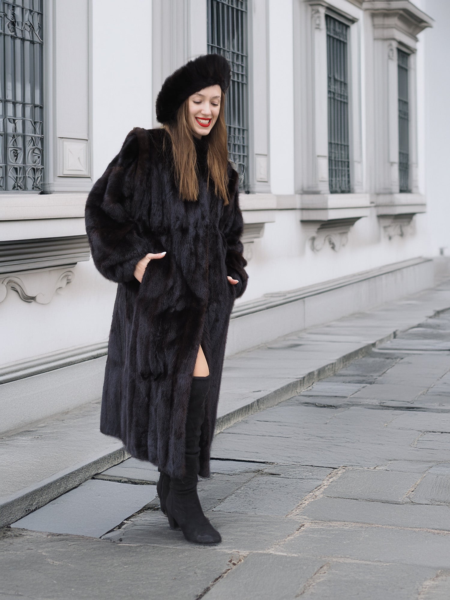 Dark ranch mink fur coat with side pockets, worn with high boots and matching hat. Warm and stylish outerwear for cold weather.