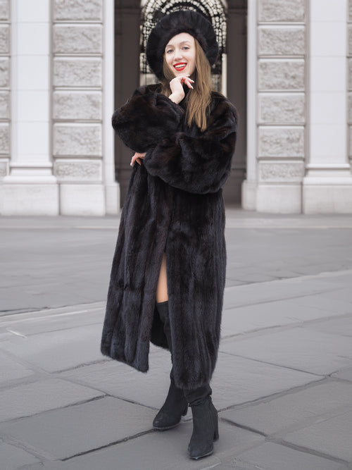 Full view of dark ranch black mink fur coat with classic design, worn with knee-high boots. Elegant and cozy fur outerwear.