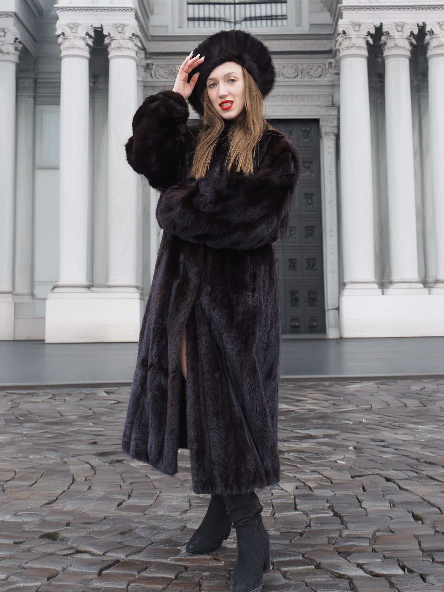Model posing in front of neoclassical architecture in a dark ranch black mink fur coat and hat. Elegant and timeless winter coat design.