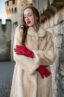 Ivory mink coat close-up: fur collar and textured sleeves, red gloves