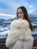 Model wearing Soft Plush Blush Fox Jacket S/M off-shoulder, showing satin lining and elegant fur texture in a snowy mountain setting.