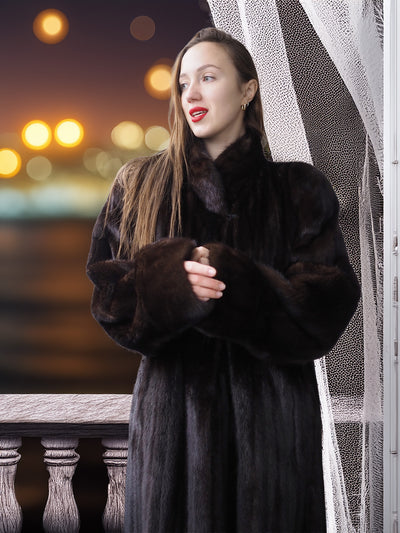 Woman wearing a dark fur coat with a blurred cityscape background