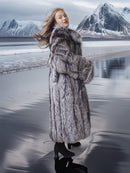 Woman in a fur coat standing on a snowy landscape with mountains in the background