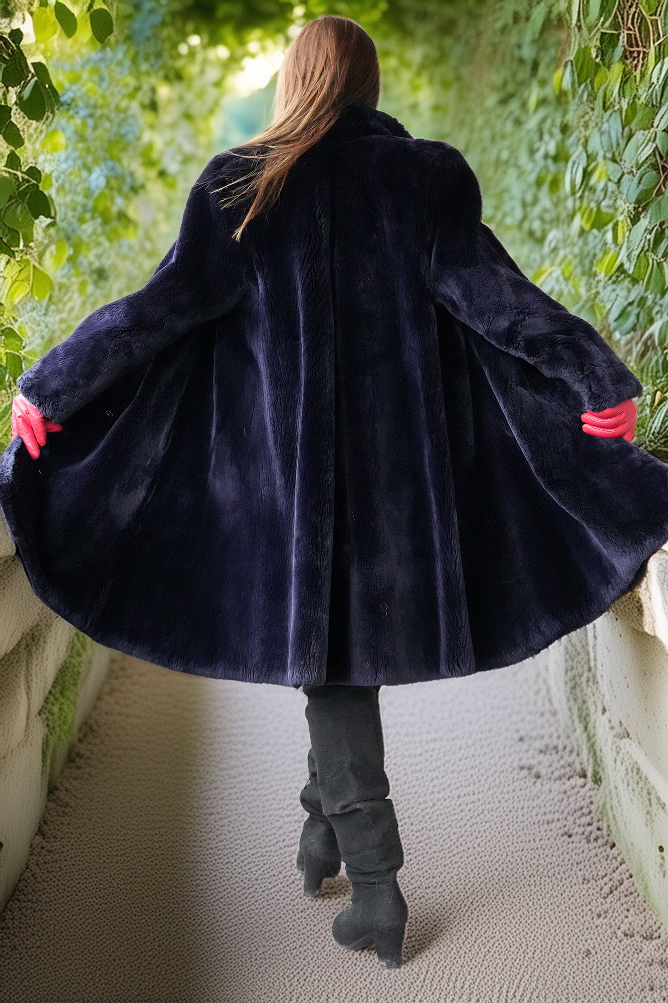 Person wearing a dark blue coat with red cuffs walking through a garden path.
