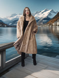 Woman in a fur coat standing on a wooden dock with mountains and a lake in the background
