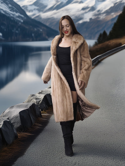 Woman in a fur coat standing on a road with a mountainous landscape in the background