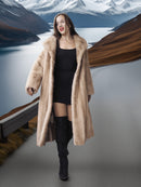 Woman in a long fur coat standing in front of a scenic mountain landscape.