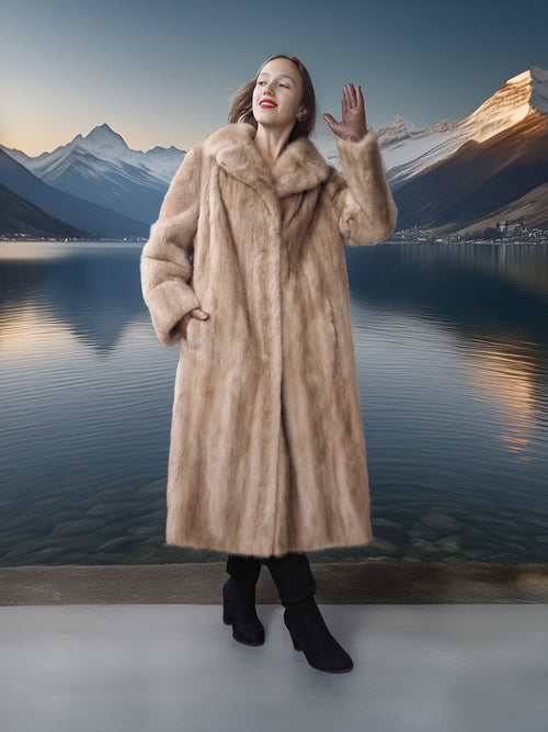 Woman in a fur coat standing in front of a scenic mountain lake.