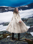 Model twirling in Two Tone Fox Coat Size XS/S on rocky terrain, showcasing the coat’s dramatic chevron fur and winter elegance.