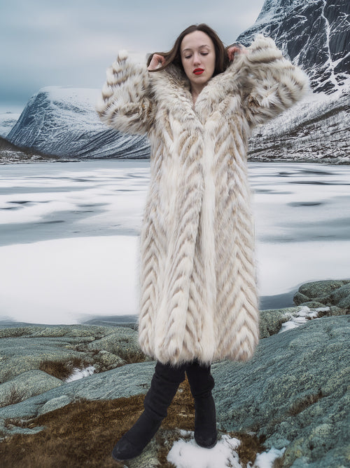 Model in Two Tone Fox Coat Size XS/S standing on icy terrain, showcasing the coat’s plush texture and chevron design for cold-weather elegance.