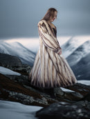 Woman in a fur coat standing on a snowy mountain landscape