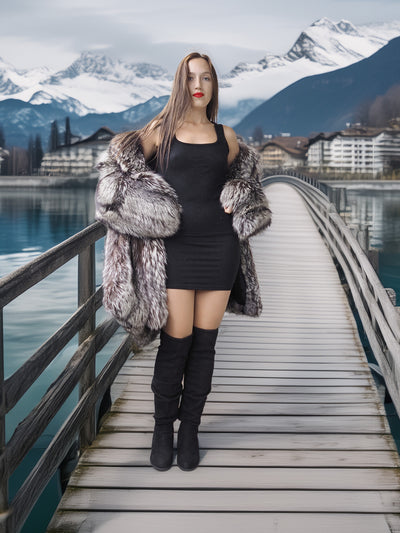 Woman in a fur coat standing on a wooden bridge with mountains and a lake in the background