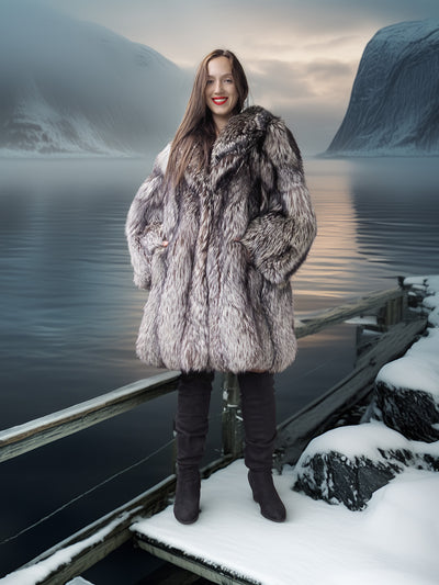 Woman in a fur coat standing on a snowy dock with a mountainous landscape in the background