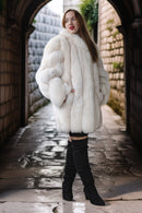 Woman wearing a white fur coat in an alleyway