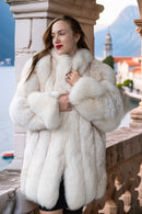 Woman wearing a white fur coat with a scenic background