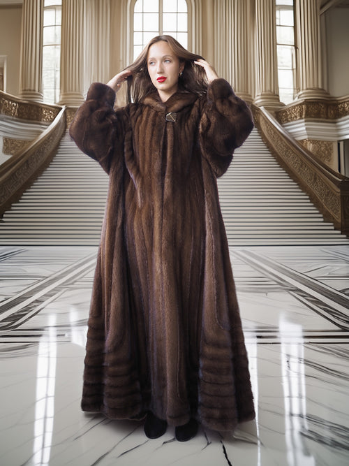 Woman in a long brown fur coat standing in an elegant interior setting.